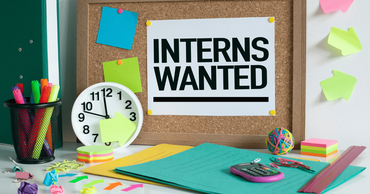 interns wanted sign above desk with clock and folders on a table