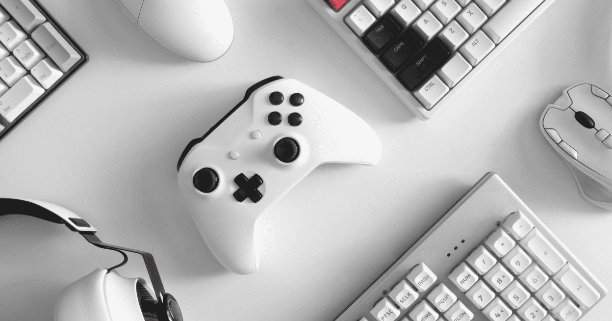 white keybooard, mouse and video game controller on awhite table