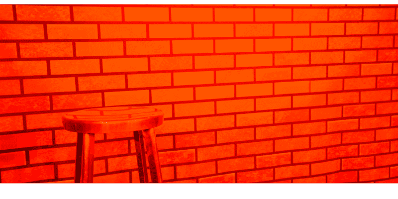 Red brick comedy stage background with empty stool.