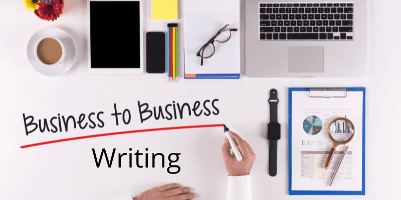 Hand at desktop writing "business to business wrting" glasses paper and watch on desktop 